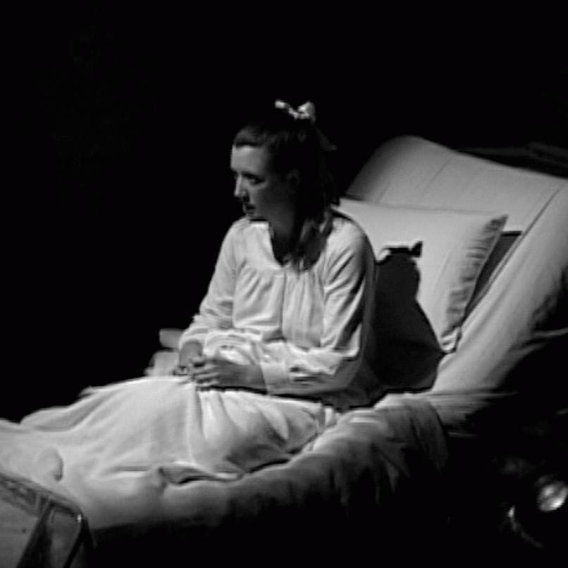 A women sitting in a hospital bed. The image is in black and white.