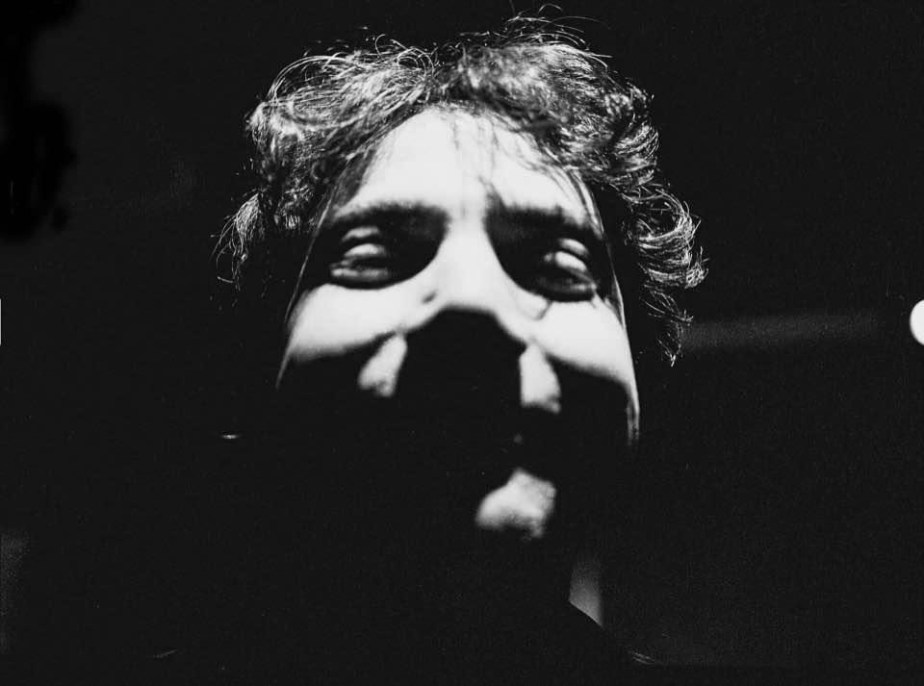 A headshot of a man in black in white with lots of shadows