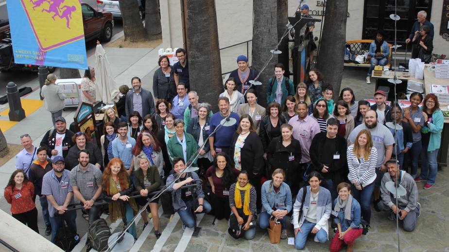 A large group shot of people looking up. Most are standing with some sitting down of a set of stairs.