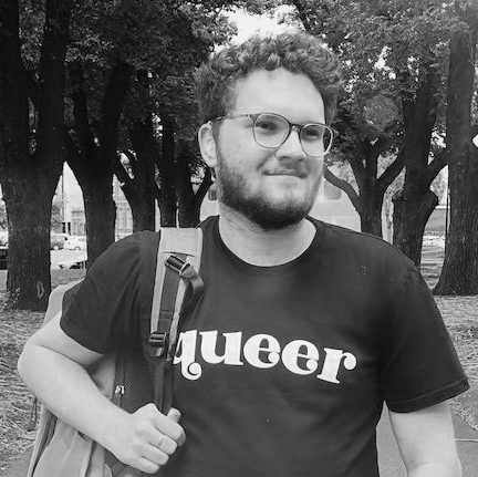 A male actor with t-shirt with the word queer written on it. The image is in black and white.